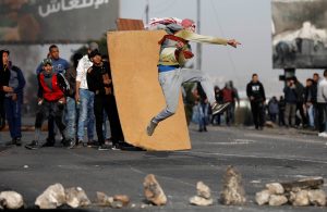 A Palestinian demonstrator hurls stones towards Israeli troops during clashes at a protest against U.S. President Donald Trump's decision to recognise Jerusalem as the capital of Israel, near the West Bank city of Nablus, December 29, 2017.