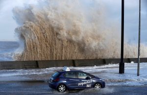 A car drives along a flooded road in New Brighton, on the coast of the Wirral peninsula, in Merseyside, Britain, January 3, 2018.