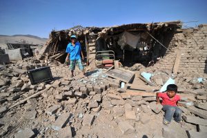 A man and a child stand at debris of a building after a strong magnitude 7.1 earthquake struck the coast of southern Peru, in Acari, Arequipa , Peru, January 14, 2018.