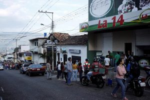 People line up outside a supermarket with its security shutters partially closed as a precaution against riots or lootings, in San Cristobal, Venezuela January 16, 2018.