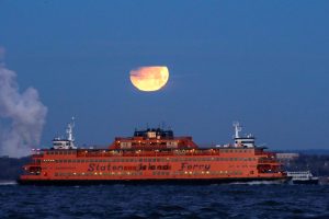 The "Super Blue Blood Moon" sets behind the Staten Island Ferry, seen from Brooklyn, New York, U.S., January 31, 2018.