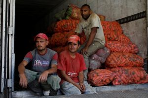 Workers pose for a picture while they load vegetables into a truck to sell them in the town of Guatire outside Caracas, in La Grita, Venezuela January 27, 2018.