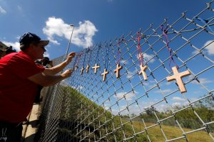 Bob Ossler, chaplain with the Cape Coral volunteer fire department, places seventeen crosses for the victims of yesterday's shooting at Marjory Stoneman Douglas High School on a fence a short distance from the school in Parkland, Florida, February 15, 2018.