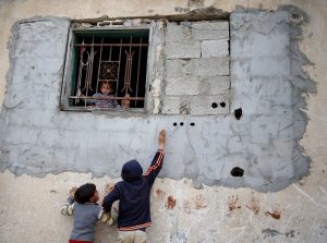 Palestinian children play as a girl held by her mother looks out of the window of house in the northern Gaza Strip February 12, 2018. REUTERS/Mohammed Salem