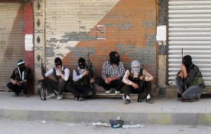 FILE PHOTO: Free Syrian Army members, with covered faces and holding weapons, sit by the side of a street in Qaboun district, Syria Damascus June 11, 2012. REUTERS/Stringer/File Photo