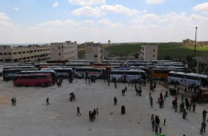 People, who were evacuated from the two rebel-besieged Shi'ite villages of al-Foua and Kefraya, stand near buses at insurgent-held al-Rashideen, Aleppo province, Syria April 19, 2017. REUTERS/Ammar Abdullah