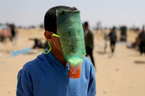 A Palestinian protects himself from inhaling tear gas at the Israel-Gaza border during a protest demanding the right to return to their homeland, in the southern Gaza Strip April 6, 2018. REUTERS/Ibraheem Abu Mustafa