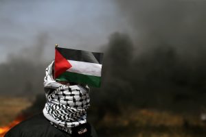 FILE PHOTO - A demonstrator with a Palestinian flag looks on during clashes with Israeli troops at the Israel-Gaza border at a protest demanding the right to return to their homeland, in the southern Gaza Strip April 6, 2018. REUTERS/Ibraheem Abu Mustafa