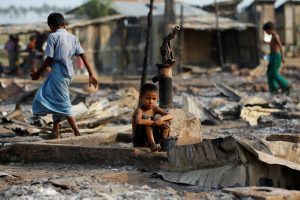 FILE PHOTO: A boy sits in a burnt area after fire destroyed shelters at a camp for internally displaced Rohingya Muslims in the western Rakhine State near Sittwe, Myanmar May 3, 2016. REUTERS/Soe Zeya Tun/File Phot