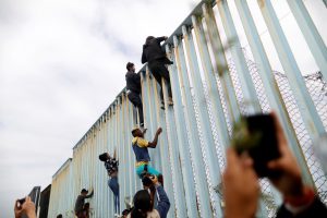 Members of a caravan of migrants from Central America climb up the border fence between Mexico and the U.S., as a part of a demonstration prior to preparations for an asylum request in the U.S., in Tijuana, Mexico April 29, 2018. REUTERS/Edgard Garrido