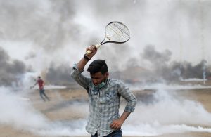 A demonstrator uses a racket to return tear gas canisters fired by Israeli troops during a protest where Palestinians demand the right to return to their homeland, at the Israel-Gaza border in the southern Gaza Strip, May 4, 2018. REUTERS/Ibraheem Abu Mustafa
