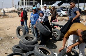A Palestinian woman drops tyres to be burnt at the Israel-Gaza border during a protest where Palestinians demand the right to return to their homeland, in the southern Gaza Strip May 11, 2018. REUTERS/Ibraheem Abu Mustafa