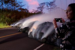 A news reporter takes pictures of the Kilauea lava flow that crossed Pohoiki Road near Highway 132, near Pahoa, Hawaii, U.S., May 28, 2018. REUTERS/Marco Garcia