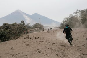 A police officer runs away from a new pyroclastic flow spewed by the Fuego volcano in the community of San Miguel Los Lotes in Escuintla, Guatemala, June 4, 2018. REUTERS/Luis Echeverria