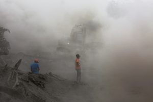 Residents are seen amidst ashes as heavy machinery removes ash from a road at an area affected by the eruption of the Fuego volcano at El Rodeo in Escuintla, Guatemala June 6, 2018. Picture taken June 6, 2018. REUTERS/Carlos Jasso