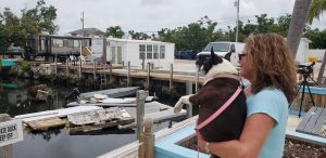 Terri Metter and her Boston Terrier Nikki overlook what's left of destroyed trailers that fill a canal near a trailer park in Marathon, Florida, U.S., June 10, 2018. REUTERS/Zach Fagenson
