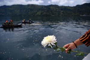 A relative of missing passengers of a ferry that sank holds a flower before throwing it into Lake Toba in Simalungun, North Sumatra, Indonesia July 2, 2018. Antara Foto/Sigid Kurniawan/via REUTERS
