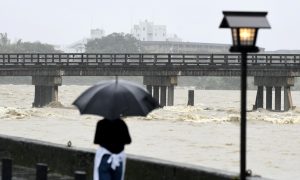 A local resident watches Togetsu Bridge and swollen Katsura River, caused by a heavy rain, in Kyoto, western Japan, in this photo taken by Kyodo July 6, 2018. Mandatory credit Kyodo/via REUTERS