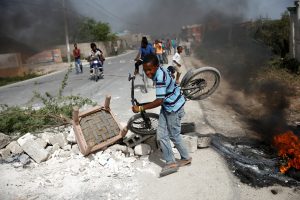 A boy carrying his bicycle passes through a barricade on the outskirts of Croix-des-Bouquets, Haiti, July 8, 2018. REUTERS/Andres Martinez Casares