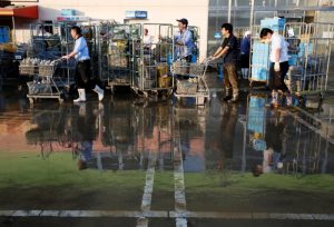 Employees of a supermarket push trolleys and shelves, with muddy items, at their store in a flooded area in Mabi town in Kurashiki, Okayama Prefecture, Japan, July 9, 2018. REUTERS/Issei Kato