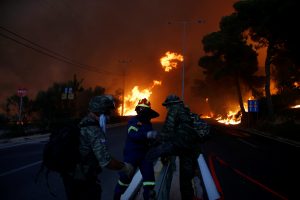 Firefighters and soldiers fall back as a wildfire burns in the town of Rafina, near Athens, Greece, July 23, 2018. REUTERS/Costas Baltas