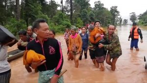 People walk through flooded area after being brought to safety by boat in Sanam Xay district, Attapeu Province, Laos after a hydropower dam under construction in Southern Laos collapsed, in this still picture taken from social media video obtained July 24, 2018. ATTAPEU TODAY/ via REUTERS