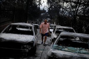 A man walks among burnt cars following a wildfire at the village of Mati, near Athens. REUTERS/Alkis Konstantinidis