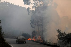 A car passes next to a fire near small village of Monchique, Portugal August 6, 2018. REUTERS/Rafael Marchante