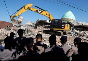 Policemen stand as heavy equipment move debris for try to find people trapped inside a mosque after an earthquake hit on Sunday in Pemenang, Lombok Island, Indonesia, August 8, 2018. REUTERS/Beawiharta