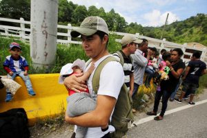A man carries a baby as he walks with other Hondurans fleeing poverty and violence as they move in a caravan toward the United States, in the west side of Honduras October 14, 2018. REUTERS/ Jorge Cabrera