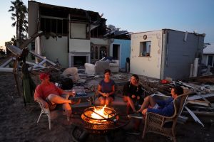 A family sits by a fire and prepares to eat a dinner of MREs in front of their house with no roof following Hurricane Michael in Mexico Beach, October 13. REUTERS/Carlo Allegri