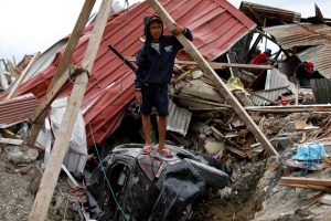 Ikhmal Yudanto, 15, stands on his mother's car at his destroyed house hit by an earthquake, in Balaroa neighbourhood, Palu, Central Sulawesi, Indonesia, October 11, 2018. REUTERS/Jorge Silva