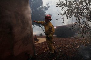 A Cal Fire firefighter hoses a smoldering home while battling the Camp Fire in Paradise, California, U.S. November 8, 2018. REUTERS/Stephen Lam