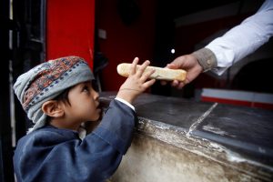 A worker gives a boy bread at a Mercy charitable bakery in Sanaa, Yemen November 9, 2018. Picture taken November 9, 2018. REUTERS/Mohamed al-Sayaghi