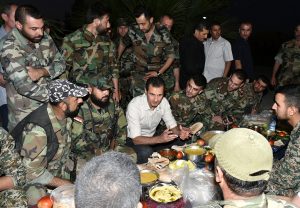 FILE PHOTO: Syria's president Bashar al-Assad (C) joins Syrian army soldiers for Iftar in the farms of Marj al-Sultan village, eastern Ghouta in Damascus, Syria in this handout picture provided by SANA on June 26, 2016./File Photo
