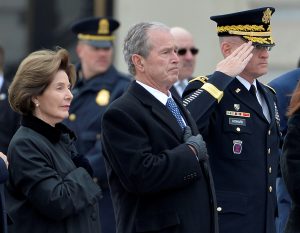 Former President George W. Bush places his hand over his heart with Laura Bush as they watch the casket of the late former President George H.W. Bush depart the U.S. Capitol enroute to the National Cathedral for funeral services, Washington, U.S., December 5, 2018. REUTERS/Mike Theiler