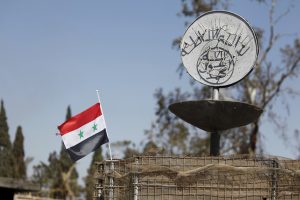 FILE PHOTO: A Syrian national flag flutters next to the Islamic State's slogan at a roundabout where executions were carried out by ISIS militants in the city of Palmyra, in Homs Governorate, Syria in this April 1, 2016 file photo. Omar Sanadiki/Files/File Photo