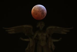 The moon is seen over "Victoria Alada" statue on the top of Metropoli building during a total lunar eclipse, known as the "Super Blood Wolf Moon" in Madrid, Spain, January 21, 2019. REUTERS/Sergio Perez